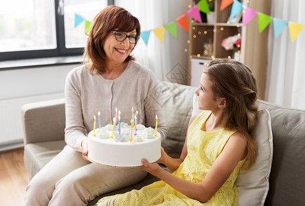 家庭,世代庆祝的快乐的祖母孙女与生日蛋糕家里聚会祖母孙女带着生日蛋糕图片