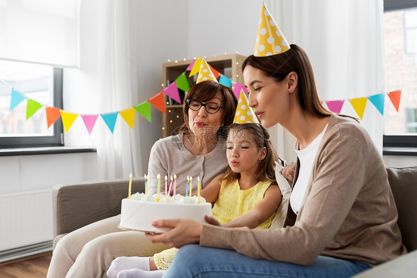 家庭,世代庆祝微笑的母亲,女儿祖母家里带生日蛋糕妈妈,女儿,奶奶带着生日蛋糕图片