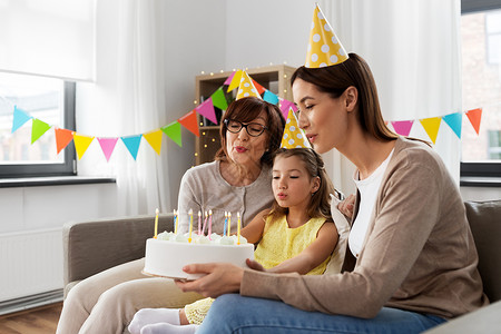 家庭,世代庆祝微笑的母亲,女儿祖母家里带生日蛋糕妈妈,女儿,奶奶带着生日蛋糕图片