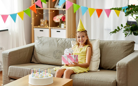 童庆祝快乐的女孩戴着生日礼物蛋糕家快乐的女孩戴着派帽,家里生日礼物图片