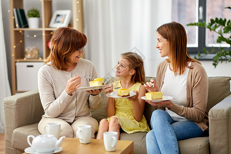 家庭世代食物微笑的母亲女儿祖母家里举行茶会吃蛋糕母亲女儿祖母吃蛋糕图片