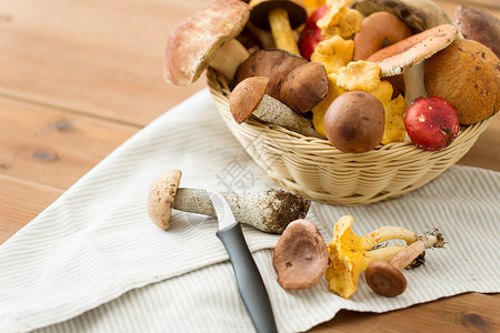 烹饪收获篮子同的食用蘑菇,菜刀毛巾木桌上同食用菌刀的篮子图片