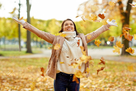 季节人们的快乐的轻女人扔枫叶玩秋天的公园快乐的女人秋天的公园里玩树叶图片