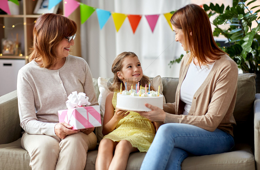 家庭世代庆祝微笑的母亲女儿祖母带着礼品盒生日蛋糕,家里十支蜡烛母亲女儿祖母生日图片