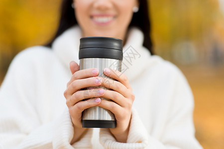 季节,热饮人们的接近快乐的轻女人喝咖啡热杯倒翁秋天公园快乐的轻女人秋天的公园喝咖啡背景图片