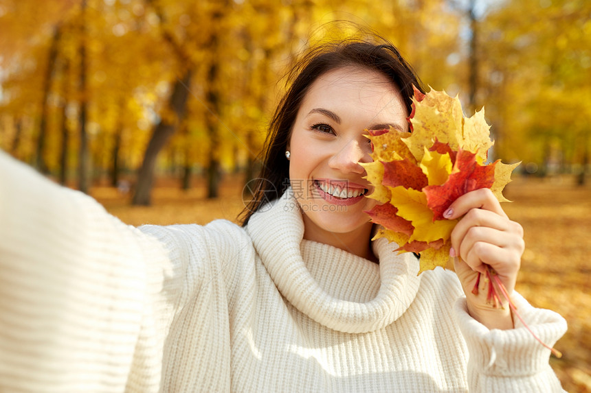 季节人们的快乐的轻女人带着枫叶秋天的公园自拍树叶的女人秋天的公园自拍图片