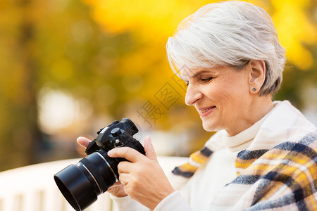 老退休人们的观念快乐的老妇女秋天公园拍照秋天公园带照片相机的高级女人图片