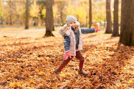 童,季节人的快乐的小女孩与枫叶秋天公园跑步快乐的女孩秋天的公园枫叶跑步图片