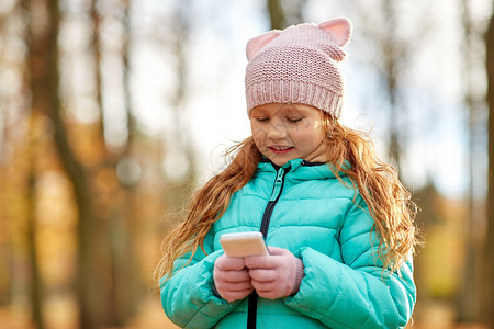 童,季节人的快乐的女孩与智能手机秋天公园秋天公园智能手机的女孩图片