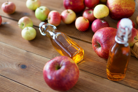 水果饮料季节璃瓶的苹果汁,苹果酒醋木制桌子上木制桌子上的苹果汁醋瓶背景