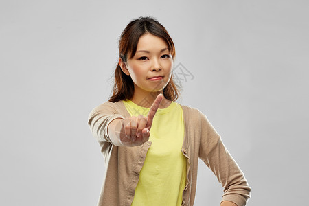 人,禁止拒绝轻的亚洲妇女威胁手指灰色背景轻的亚洲女人用手指威胁图片