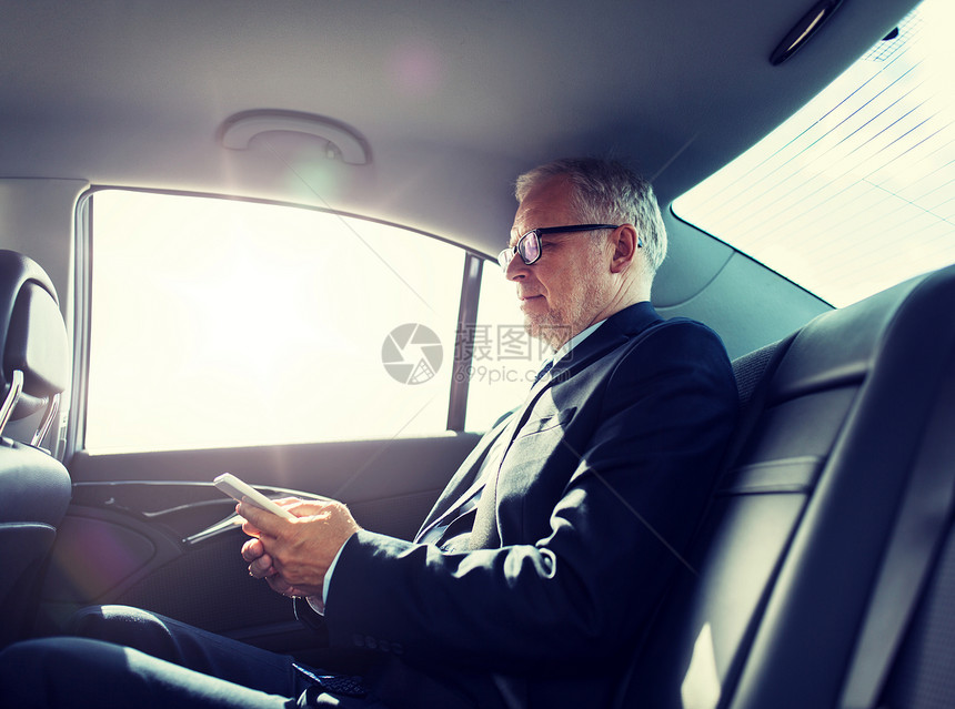 交通,商务旅行,技术人的高级商人智能手机上发短信汽车后座上开车高级商人车里用智能手机发短信图片