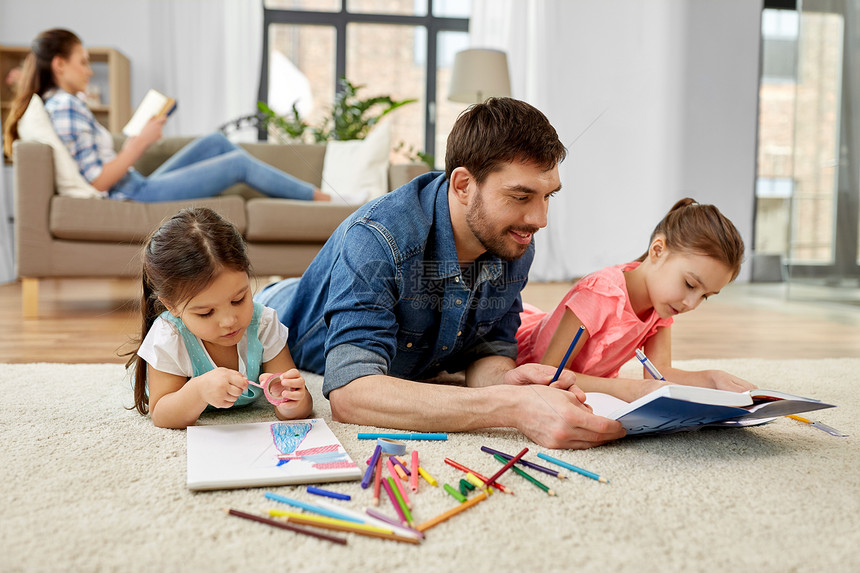 家庭母亲休闲父亲花时间她的小女儿画画,并帮助家庭作业躺家里的地板上父亲花时间小女儿家里图片