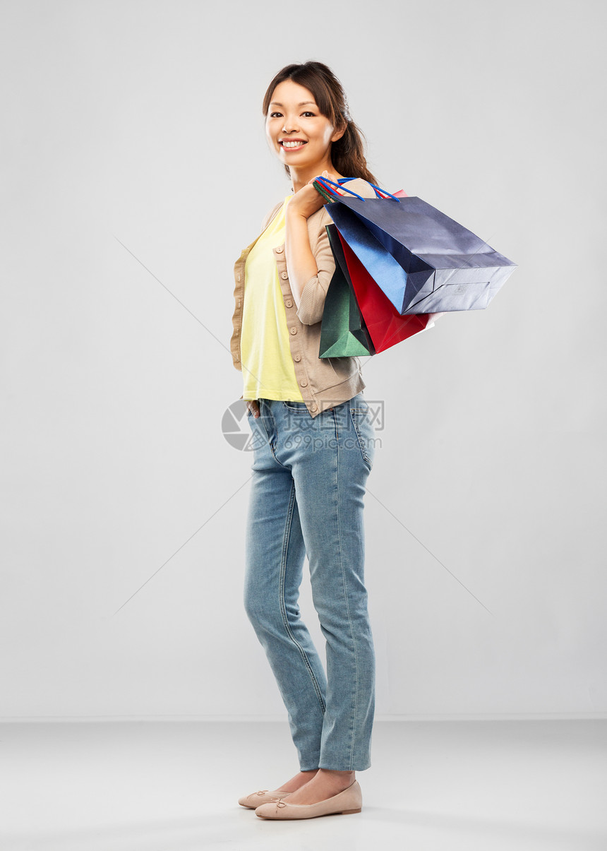 销售,出口消费主义快乐的亚洲轻妇女与购物袋灰色背景带购物袋的快乐亚洲女人图片