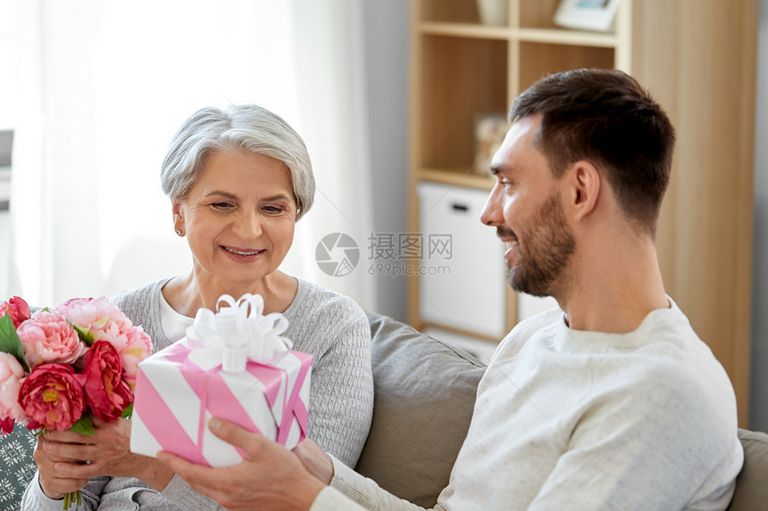 家庭母亲生日的微笑的成儿子家里给他的老母亲送礼物鲜花儿子给迈的母亲送礼物鲜花图片