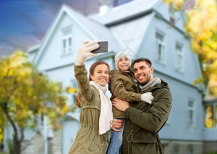 房子照片素材家庭休闲人的快乐的母亲,父亲小女儿秋天的背景下,智能手机家里自拍家人秋天用智能手机房子自拍背景
