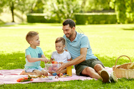 家庭休闲人的快乐的父亲两个小儿子夏季公园野餐快乐的家庭夏天的公园野餐图片