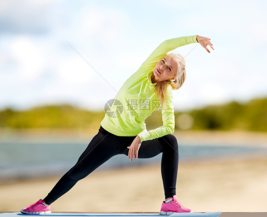 健身,运动健康的生活方式妇女伸展运动垫夏季海滩背景女人海滩上的运动垫上伸展图片