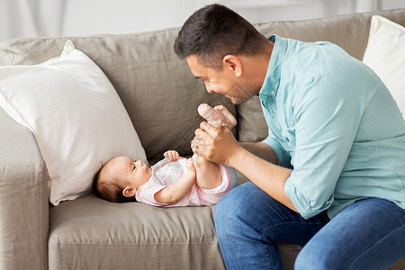 家庭父母父亲的快乐微笑的中父亲小女儿躺家里的沙发上玩耍中父亲家玩婴儿图片