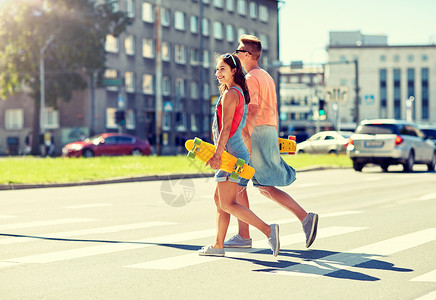短道急转暑假,极限运动人们的快乐的青少夫妇与短现代巡洋舰滑板穿越城市人行横道轻夫妇城市街道上滑板背景