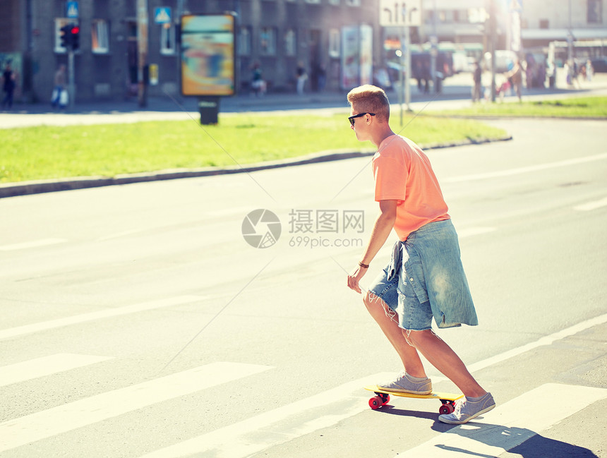 暑假,极限运动人的十几岁的男孩骑着短现代巡洋舰滑板城市人行横道十几岁的男孩滑板上穿过城市人行横道图片