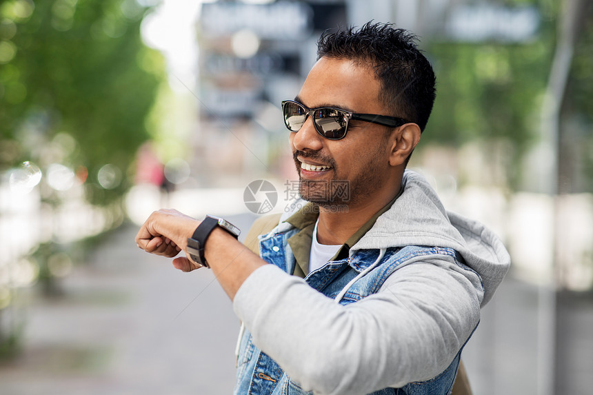 旅行,旅游生活方式的微笑的印度男子用语音命令记录器智能手表城市街道印度男子用智能手表录制语音信息图片