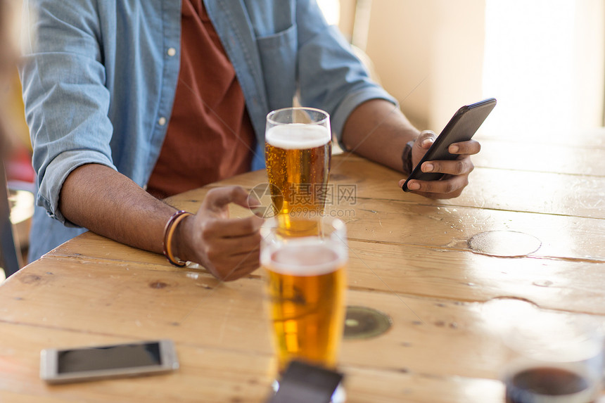 人技术智能手机的人酒吧酒吧喝啤酒阅读信息智能手机的男人酒吧酒吧喝啤酒图片