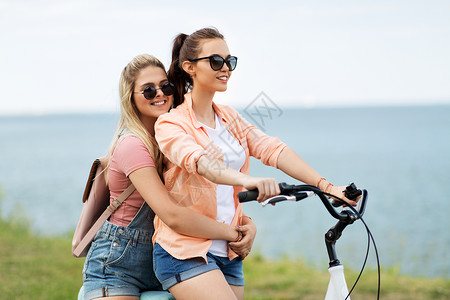 海边兜风休闲友谊的快乐微笑的十几岁女孩朋友骑自行车海边夏天夏天十几岁的女孩朋友骑自行车背景