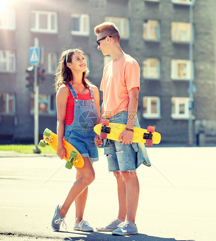 暑假,极限运动人们的快乐的青少夫妇与短现代巡洋舰滑板城市街道上交谈轻夫妇城市街道上滑板图片