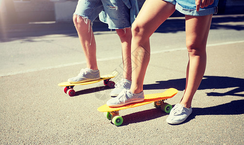 时髦的巡洋舰夏天,极限运动人的十几岁的夫妇骑着短的现代巡洋舰滑板城市街道轻夫妇城市街道上骑滑板背景