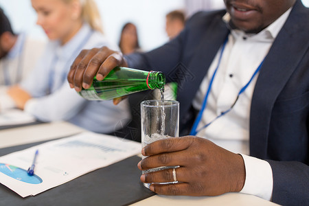 商业人的非裔美国商人会议上把水瓶子倒璃商人会议上给璃倒水图片