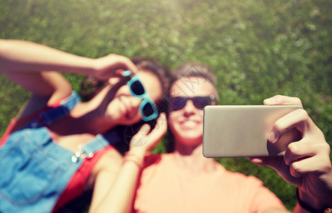 快乐的夫妇戴着太阳镜躺草地上自拍图片