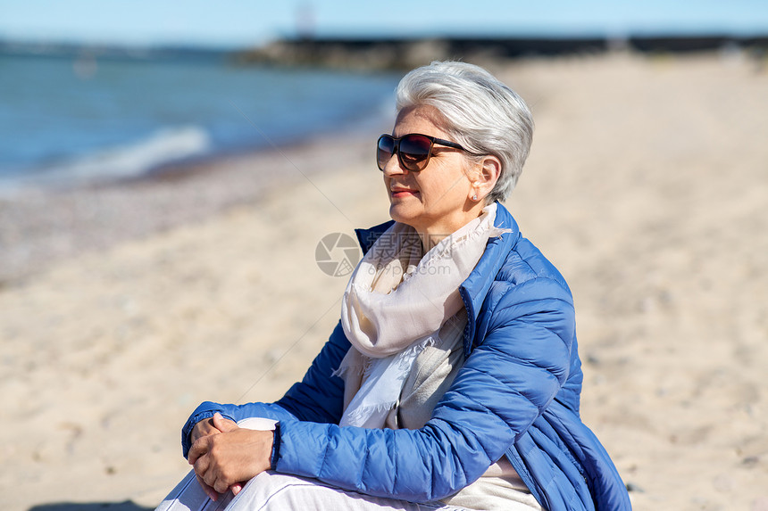 人与休闲的快乐的老妇女戴着太阳镜夹克爱沙尼亚的海滩上快乐的高级女人穿着夹克海滩上图片