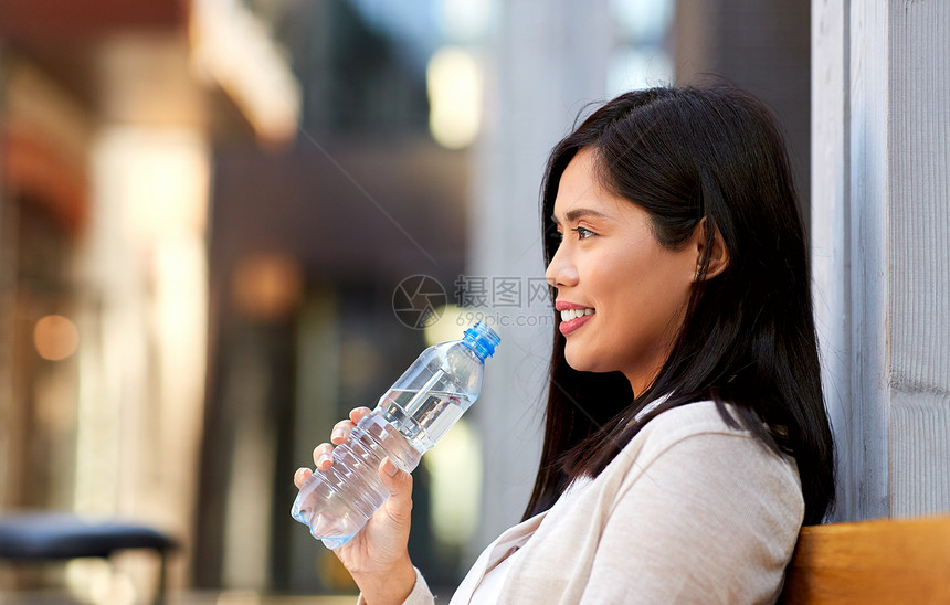 生活方式人们的快乐微笑的轻亚洲妇女喝水,粉塑料瓶坐木城长凳上女人喝水坐木城长凳上图片