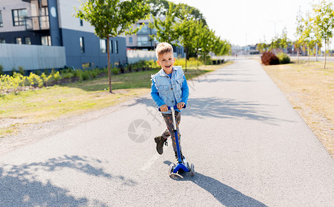 童,休闲趣的快乐的小男孩骑滑板车城市快乐的小男孩城市里骑滑板车背景