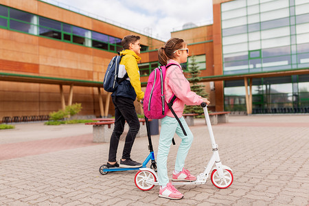 教育,童人的快乐的学校孩子与背包骑滑板车户外带背包的学童骑滑板车图片