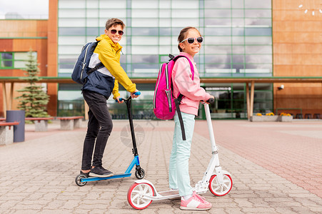 教育,童人的快乐的学校孩子与背包骑滑板车户外带背包的学童骑滑板车背景图片