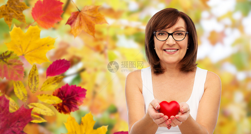 秋天背景下的老年妇女捧着红心图片