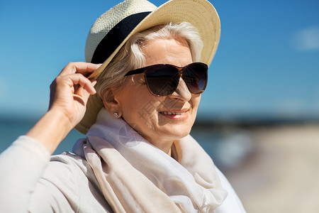 波罗人人休闲爱沙尼亚海滩上戴太阳镜草帽的快乐老妇女的肖像快乐的高级女人戴着太阳镜帽子海滩上背景