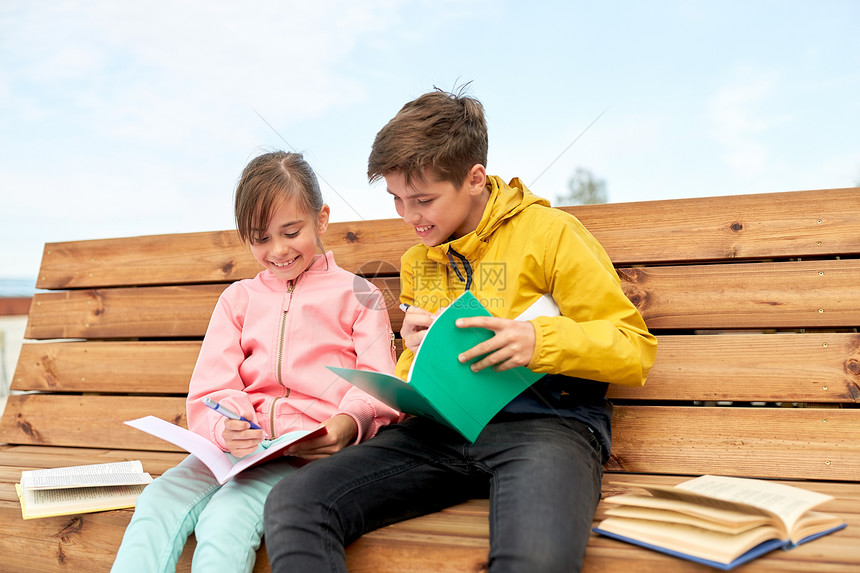 教育,童人的快乐的学校孩子兄弟姐妹,笔记本书坐木制的街道长凳上户外学校的孩子们着笔记本坐长凳上图片