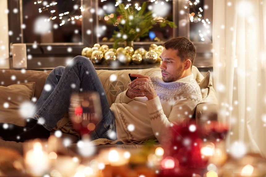 诞节,技术假期男人与智能手机短信家里的雪带智能手机的男人家里过诞节图片