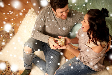 诞节,假日人们的幸福的夫妇家里的礼品盒雪上家里礼品盒的幸福夫妇背景图片