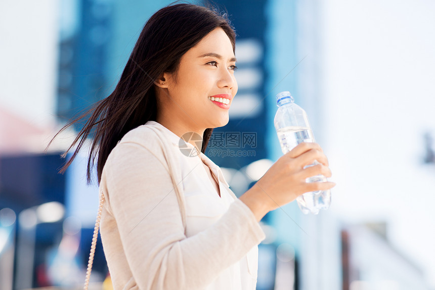 生活方式人们的轻的亚洲妇女饮用水粉塑料瓶城市亚洲女人城市的瓶子里喝水图片