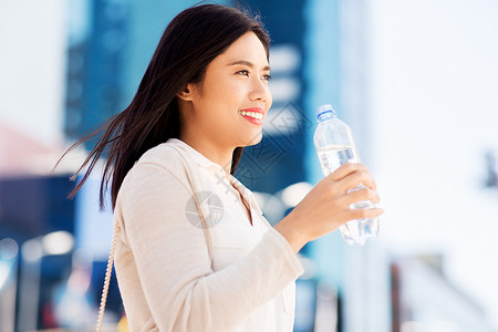 生活方式人们的轻的亚洲妇女饮用水粉塑料瓶城市亚洲女人城市的瓶子里喝水图片