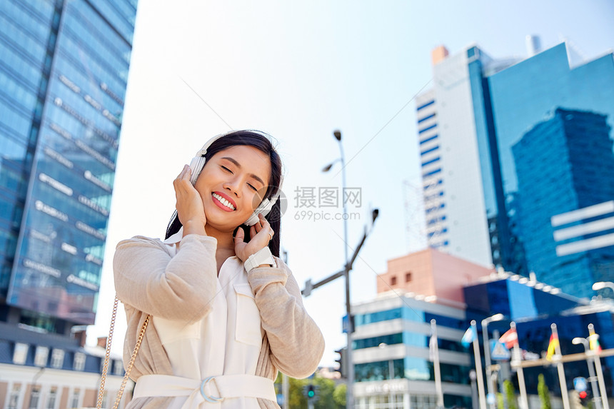 技术,休闲人的快乐的微笑亚洲妇女戴着耳机城市听音乐城市里带着耳机的快乐微笑的亚洲女人图片