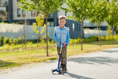 童,休闲趣的快乐的小男孩骑滑板车城市快乐的小男孩城市里骑滑板车背景图片