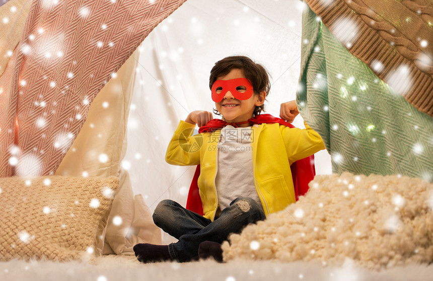 童诞节的快乐的小男孩戴着超级英雄具斗篷孩子们的帐篷帐篷家里的雪上快乐的男孩穿着超级英雄斗篷,孩子们的图片