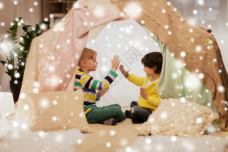 童诞节友谊的快乐的男孩孩子们的帐篷雪上的帐篷里玩拍手游戏男孩孩子们的帐篷里玩拍手游戏背景图片