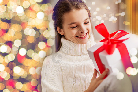 送财童童,假日人的快乐的美丽女孩与诞礼品盒节日灯的背景快乐的美丽女孩家里送诞礼物背景