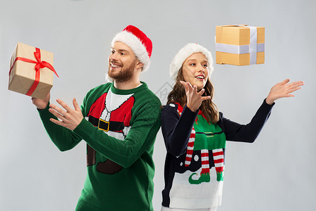 派礼物人节日的幸福的夫妇戴着诞帽,毛衣派上诞礼物诞毛衣里的幸福夫妇带着礼物背景